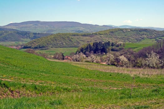 Green fields with slopy mountains in the background.