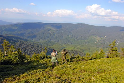 Two hunters watching the territory in the mountains, clouds in distance