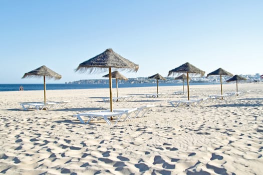 Thatched umbrellas and beach chairs on the beach near Lagos Portugal