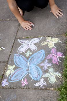 Pavement with a butterfly chalkdrawing and hands of a child