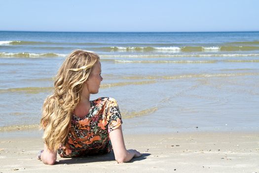 Beautiful blonde woman relaxing at the waterfront of the north sea in the Netherlands