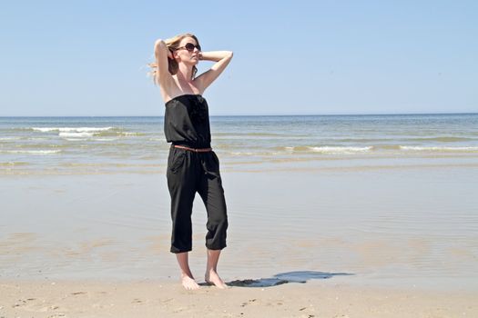 Beautiful blonde woman relaxing at the waterfront of the north sea in the Netherlands