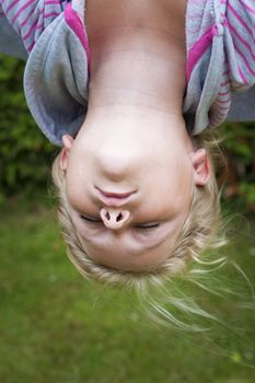 A girl haning upside down with eyes closed. 