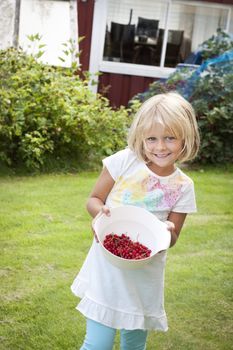 Happy child with a bowl of freshly picked berries