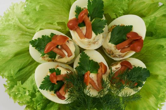 Cooked stuffed eggs decorated with pickled mushrooms on salad leaves