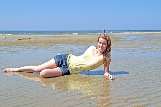 Young blonde woman lying in the water from the north sea in the Netherlands