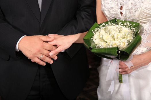 Bride holding groom's hand and the bouquet at their wedding