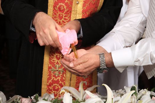 priest add oil at an orthodox christening