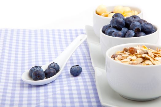fresh blueberry in white porcelain spoon with bowl of cornflakes, on serviette