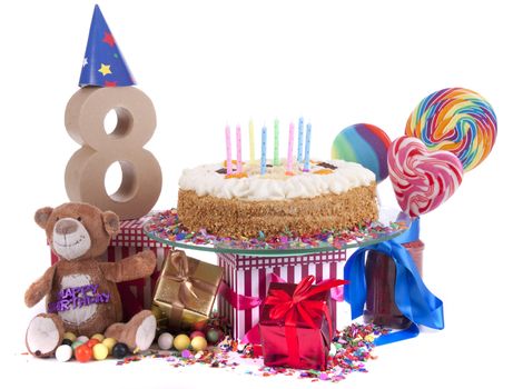 Number of age in a colorful studio setting with paper party hats, a red heart and gifts on a bottom of confetti and sweet cake with candles 