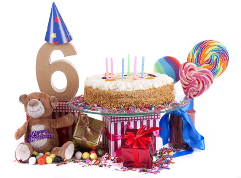 Number of age in a colorful studio setting with paper party hats, a red heart and gifts on a bottom of confetti and sweet cake with candles 