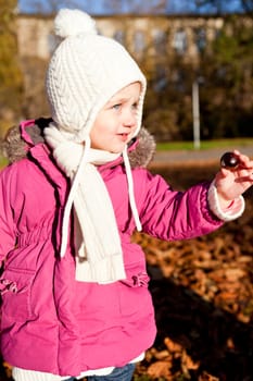 cute littloe girl playing outdoor in colorfull autumn park