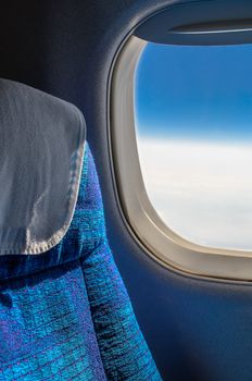 View of the blue sky from the airplane window, empty seats.