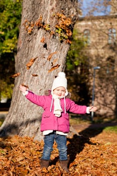 cute littloe girl playing outdoor in colorfull autumn park