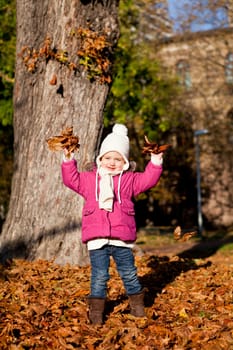 cute littloe girl playing outdoor in colorfull autumn park