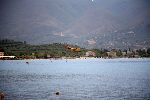 ZAKYNTHOS, GREECE- AUG 1: Canadair CL-415 or Bombardier 415 approaching the sea to take water during big fire at the mountain close to the village Alykes, August 01, 2012 Zakynthos, Greece