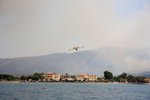 ZAKYNTHOS, GREECE- AUG 1: Canadair CL-415 or Bombardier 415 approaching the sea to take water during big fire at the mountain close to the village Alykes, August 01, 2012 Zakynthos, Greece