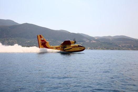 ZAKYNTHOS, GREECE- AUG 1: Canadair CL-415 or Bombardier 415 approaching the sea to take water during big fire at the mountain close to the village Alykes, August 01, 2012 Zakynthos, Greece