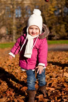 cute littloe girl playing outdoor in colorfull autumn park