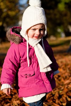 cute littloe girl playing outdoor in colorfull autumn park