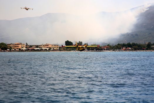 ZAKYNTHOS, GREECE- AUG 1: Canadair CL-415 or Bombardier 415 approaching the sea to take water during big fire at the mountain close to the village Alykes, August 01, 2012 Zakynthos, Greece