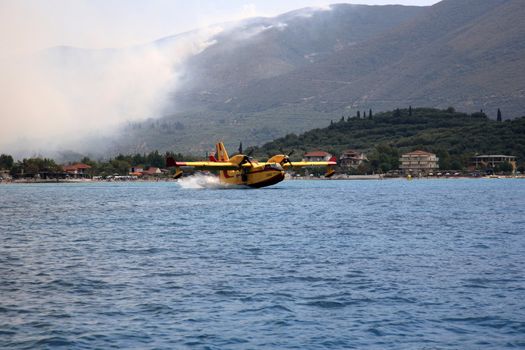 ZAKYNTHOS, GREECE- AUG 1: Canadair CL-415 or Bombardier 415 approaching the sea to take water during big fire at the mountain close to the village Alykes, August 01, 2012 Zakynthos, Greece