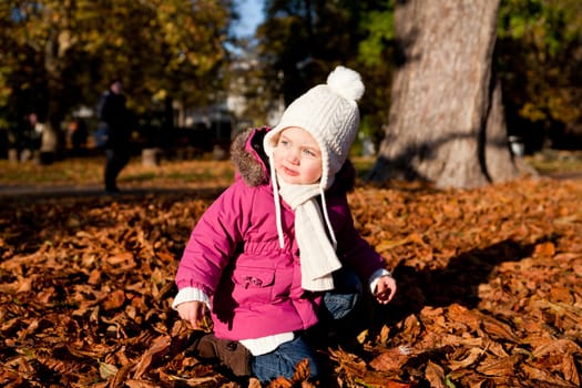 cute littloe girl playing outdoor in colorfull autumn park