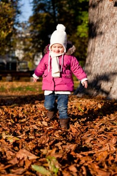cute littloe girl playing outdoor in colorfull autumn park
