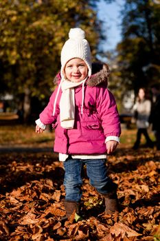 cute littloe girl playing outdoor in colorfull autumn park