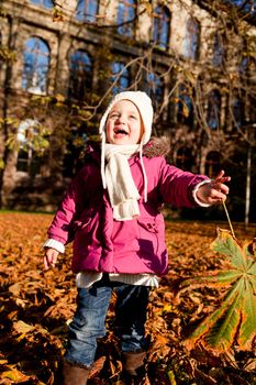 cute littloe girl playing outdoor in colorfull autumn park