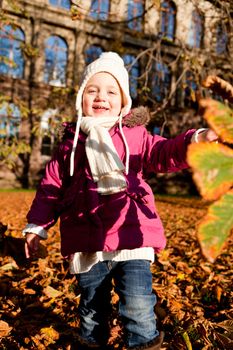 cute littloe girl playing outdoor in colorfull autumn park