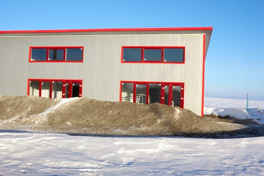Frozen construction. Unfinished building among the snow-covered field in winter