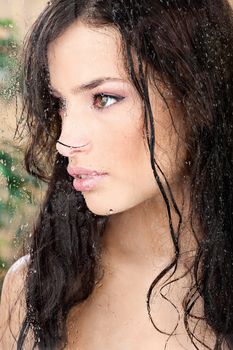 Beautiful wet girl behind glass in tropical environment