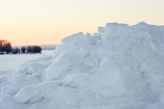 High snow hummock against the evening sky after sunset in winter