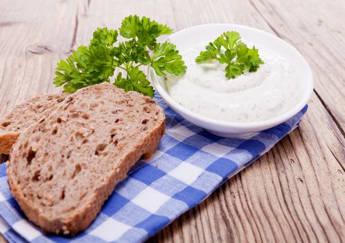 fresh tasty herbal creme cheese and bread on wooden table