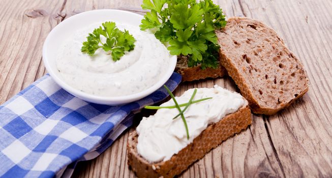 fresh tasty herbal creme cheese and bread on wooden table