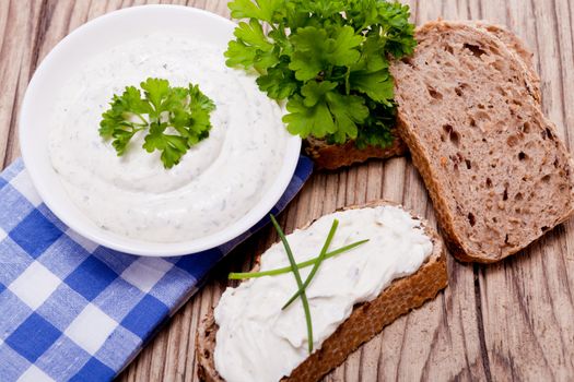 fresh tasty herbal creme cheese and bread on wooden table