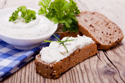 fresh tasty herbal creme cheese and bread on wooden table