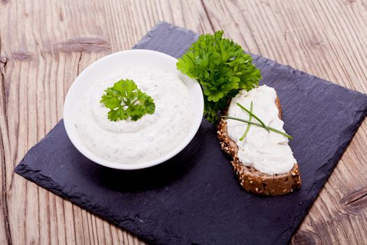 fresh tasty herbal creme cheese and bread on wooden table