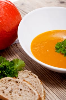 fresh tasty homemade pumpkin soup on wooden table with parsley and bread