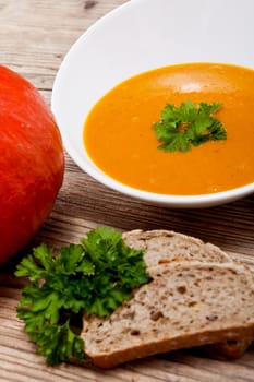 fresh tasty homemade pumpkin soup on wooden table with parsley and bread