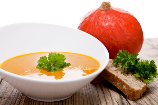 fresh tasty homemade pumpkin soup on wooden table with parsley and bread
