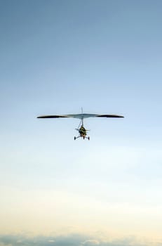 Aerial photo of motorized hang glider flying over clouds.