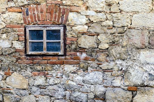 Small window on a stone wall of old house.