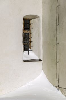 Old church window in a corner covered with snow.