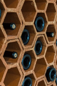 Clay wine rack with randomly placed bottles.