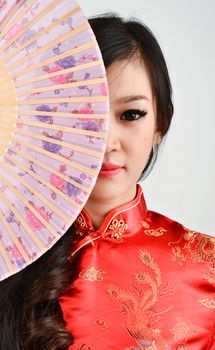 pretty women with Chinese traditional dress Cheongsam and hole Chinese Fan on gray background