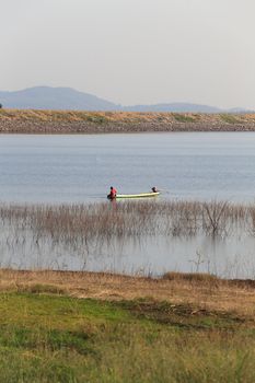 silhouette of fisherman on wood boat at lake.