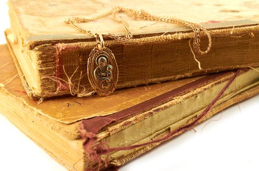 Gold chain  with pendant  of the Virgin on a background of old battered books