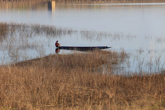 silhouette of fisherman on wood boat at lake.